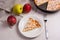 Slice of homemade apple pie with fork and fresh apples on light