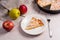 Slice of homemade apple pie with fork and fresh apples on light