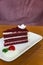 Slice of homemade velvet red cake decorated with cream on white