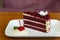 Slice of homemade velvet red cake decorated with cream on white