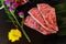 Slice Japanese beef neck chuck or jyu rosu wagyu serving on black plate and decorate with flower. Preparation for BBQ