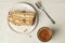 Slice of napoleon cake, glass cup of espresso coffee and a dessert silver fork on a creamy clay background top view.