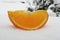 Slice of orange on ice. Orange slice on snow.