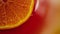 Slice of orange rotating close-up on red background