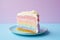 Slice of pastel rainbow colored layered birthday cake with cream in front of pastel violet and blue background