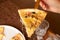 Slice of pizza with ham, mushrooms and cheese on a serving spatula and a man`s hand. Closeup