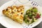 A slice of quiche with leek and feta or goats cheese on a plate with crispy leaf green salad. Vegetarian food image close up