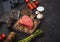 Slice of Raw Beef sirlion steak on wooden chopping board with tomatoes,garlic and asparagus tips and meat hatchet. Space for text