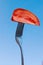 A slice of red tomato, impaled on a metal fork on a blue background,