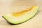 Slice of Santa Claus melon with seeds, on a clear wooden table