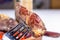 A slice of steak impaled on a fork on the background of a plate of meat