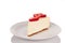 A slice of strawberry cheescake on a white plate