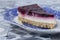Slice of summer fruit cheesecake with a biscuit base on a blue and white ornate plate.