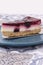 Slice of summer fruit cheesecake with a biscuit base served with a cake cutter utensil on a blue plate.