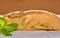 Slice of wheat bread with pesto and sprig of basil on a table.