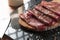 Slice of wholemeal bread with bresaola dried beef on a black granite cutting board. Bresaola is a famous Italian salami with