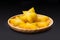 Slice of yellow star fruit on the wooden round tray isolated on black background