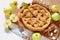 Sliced apple pie on the wooden board decorated with fresh green apples, sugar cubes, mint leaves, spices, knife and fork