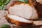 Sliced baked pork fillet and basil close-up on the table