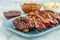 Sliced barbeque ribs on blue plate with side dishes