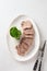 Sliced beef tongue delicacy on a white plate, beautiful classic serving with natural horseradish sauce