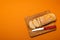 Sliced bread baguette on a wooden cutting board with knife on a terracote color background. Copy space. Close up high