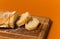 Sliced bread baguette on a wooden cutting board on a terracote color background. Close up high quality photo.