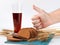 Sliced bread and wheat spikelets on bamboo mat with glass of soft drink. male hand with thumb up sign. white background