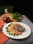 Sliced chicken breast with cream sauce and rice on a table with a serving board with spices, herbs and a bottle of olive oil