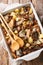 Sliced chicken with wild mushrooms, potatoes and rosemary close-up in a baking dish. Vertical top view