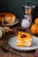 Sliced cottage cheese casserole with pumpkin layer on a ceramic plate on a brown wooden background. Pumpkin recipes. Thanksgiving