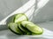 Sliced cucumbers on a white surface with sunlight