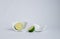 Sliced cut â€‹â€‹halves of lime in a broken half of a ceramic small platter on a white background. Place for text.