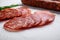 Sliced cuts of chorizo salami sausage on white textured background