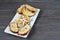 Sliced Easter bread and eggs in white plate on grey wooden board.