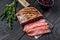 Sliced flank or bavette beef meat steak on a cleaver. Black wooden background. Top view