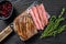 Sliced flank or bavette beef meat steak on a cleaver. Black wooden background. Top view