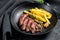 Sliced Flat Iron steak with French fries, marbled meat. Black background. Top view