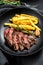 Sliced Flat Iron steak with French fries, marbled meat. Black background. Top view