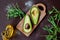 Sliced fresh avocado fruit on cutting board and olive oil bottle on table.