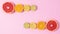 Sliced fresh citrus fruits appear on two sides on pastel pink background with copy space. Stop motion