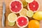 Sliced fresh citrus lemons, limes, grapefruits, oranges on a wooden cutting board with a metal knife, top view