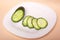 Sliced fresh cucumbers on a white plate. chopped ngherkinsn