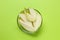 Sliced fresh pear in bowl on green background, top view. Finger food