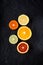 Sliced fresh ripe citruses. Lemon, lime, red orange and mandarin on a dark stone background. Top view with copy space