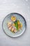 Sliced fried pork tenderloin with vegetable and passion fruit on a modern design plate