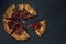 Sliced galette with ripe red cherry on dark blue textured background. Homemade sweet open pie. Top view. Space for text