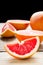 Sliced grapefruit and halves on wooden background. Useful citrus diet fruit
