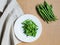 Sliced green beans on a white plate and a bunch of green beans