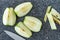 Sliced green Granny Smith apple on a plastic man made faux gray granite cutting board, chefs knife, apple quarters